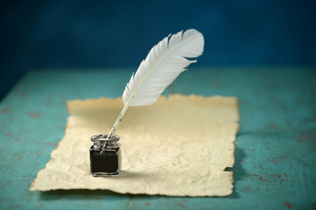 Writing Inkwell with feather and vintage paper on table