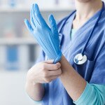 Female doctor wearing protective gloves, hands close up