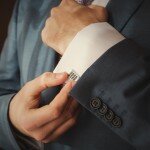 groom putting on cuff-links as he gets dressed in formal wear close up