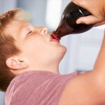 Close Up Of Boy Drinking Soda From Bottle